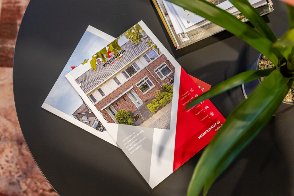 Verkoopbrochures van woningen van Wormgoor Makelaars op tafel